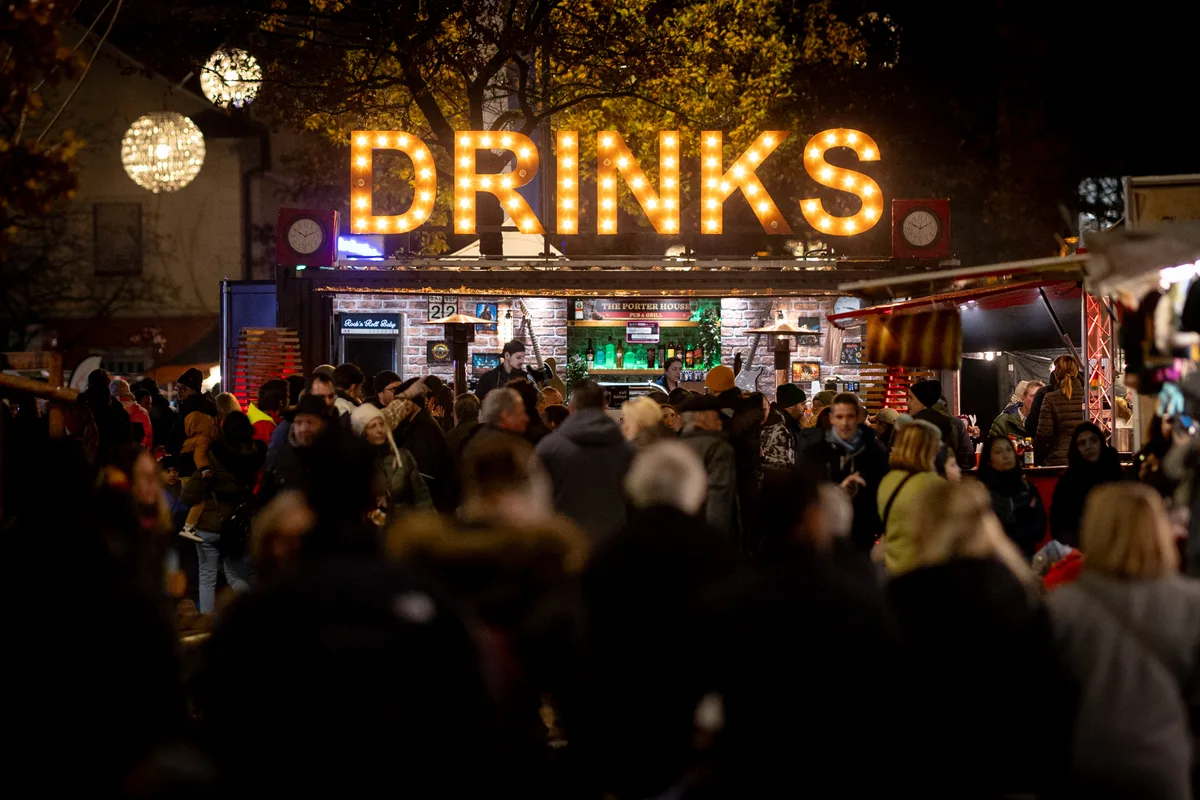 Man sieht eine grosse Menschenmenge und dahinter eine Bar mit der Überschrift «Drinks». 